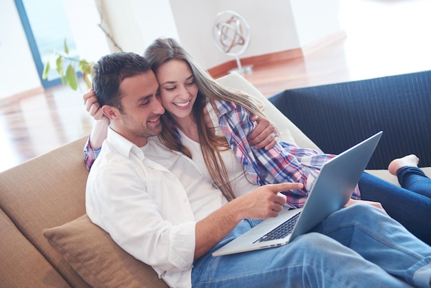 gelukkig jong ontspannen paar dat aan laptop computer bij modern huisbinnenland werkt