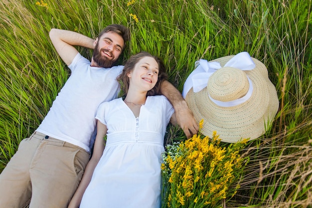 Gelukkig jong ontspannen paar verliefd dat op het gras boven je hoofd ligt