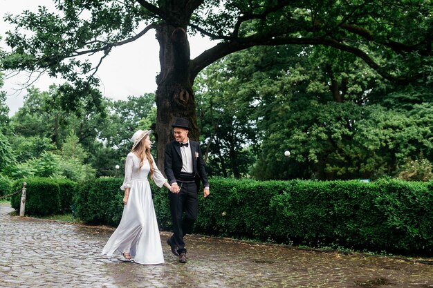 Gelukkig jong paar Bruiden in hoeden Jong meisje in een witte trouwjurk en hoed met een boeket bloemen Bruiden in het kasteel Bruid en bruidegom