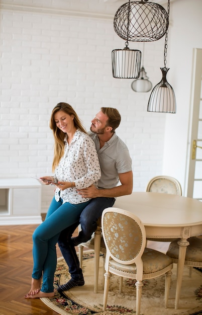 Gelukkig jong paar dat digitale tablet in woonkamer bekijkt