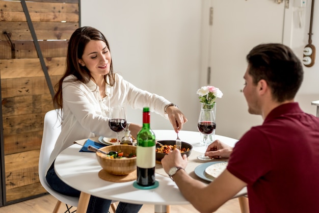 Gelukkig jong paar dat en wijn thuis eet drinkt