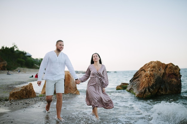 Gelukkig jong paar dat op strand dichtbij zee loopt Huwelijksreis?