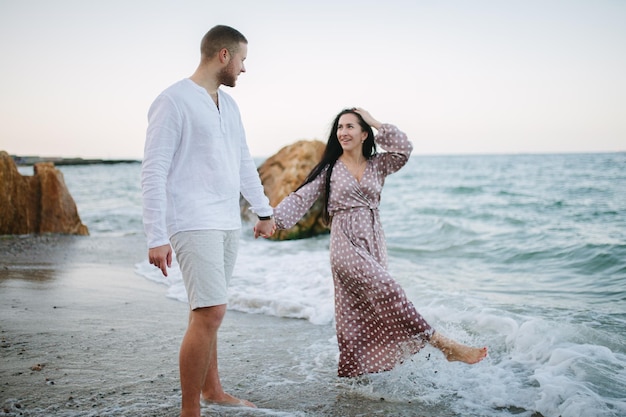 Gelukkig jong paar dat op strand dichtbij zee loopt Huwelijksreis?