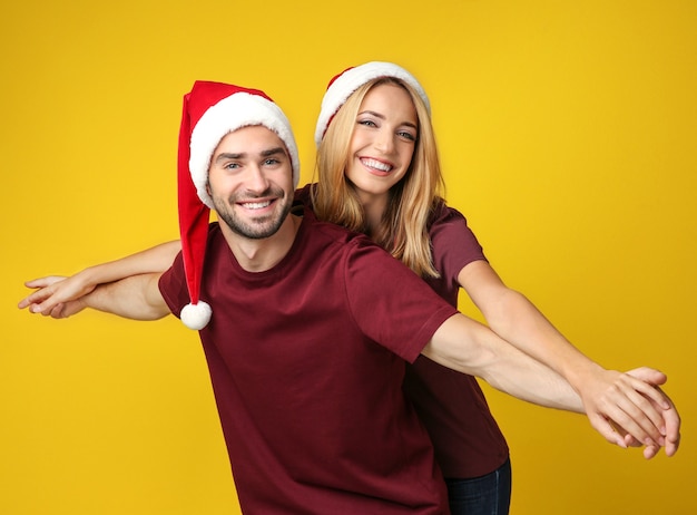 Gelukkig jong paar in Kerstmanhoeden op geel