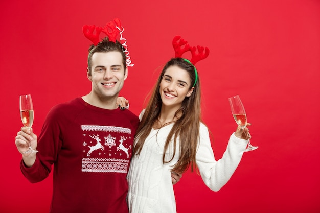 Gelukkig jong paar in sweaters die Kerstmis met Champagne vieren.