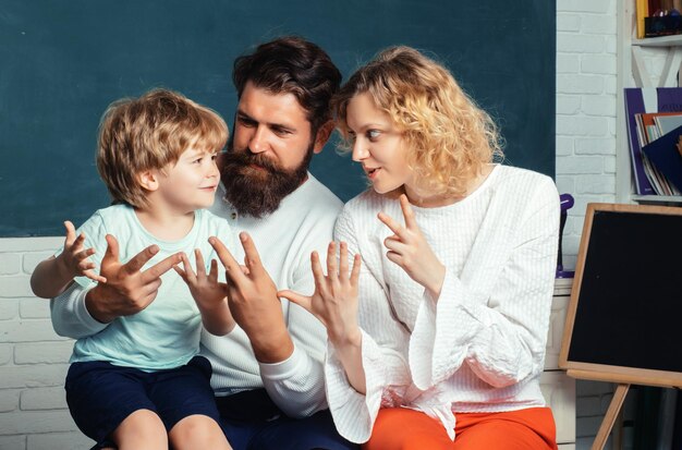 Gelukkig jong stel dat met hun zoon bij het afstuderen staat en leerlingen op schoolschool ondersteunt