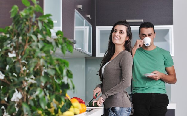 gelukkig jong stel heeft plezier in de moderne keuken binnenshuis terwijl ze verse groenten en fruit salade bereiden