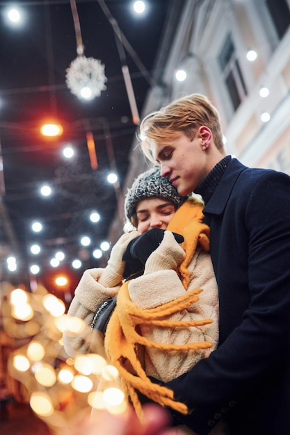 Gelukkig jong stel in warme kleren is samen op kerst versierde straat.