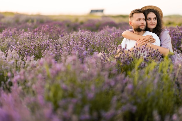 Gelukkig jong stel met een romantische date op het lavendelveld zitten en knuffelen