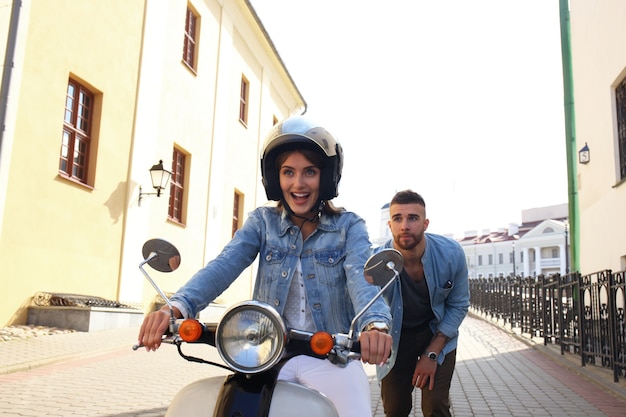 Gelukkig jong stel scooter rijden in de stad. Knappe jongen en jonge vrouw reizen. Avontuur en vakanties concept.