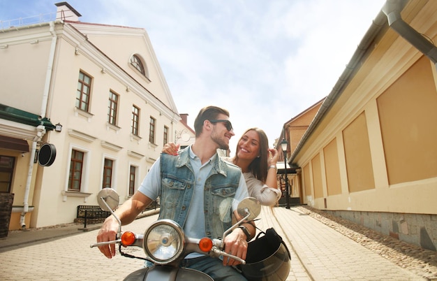 Gelukkig jong stel scooter rijden in de stad. Knappe jongen en jonge vrouw reizen. Avontuur en vakanties concept.