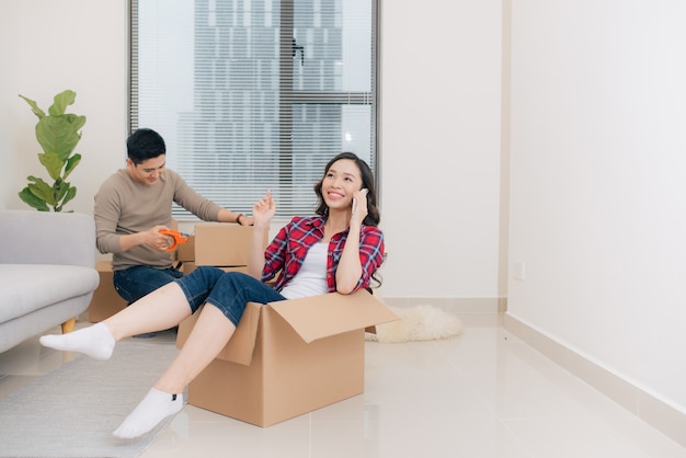Gelukkig jong stel verhuizen naar hun nieuwe appartement, hebben plezier en rijden in kartonnen dozen in een nieuw huis