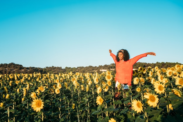 Gelukkig jong zwarte die op een zonnebloemgebied lopen