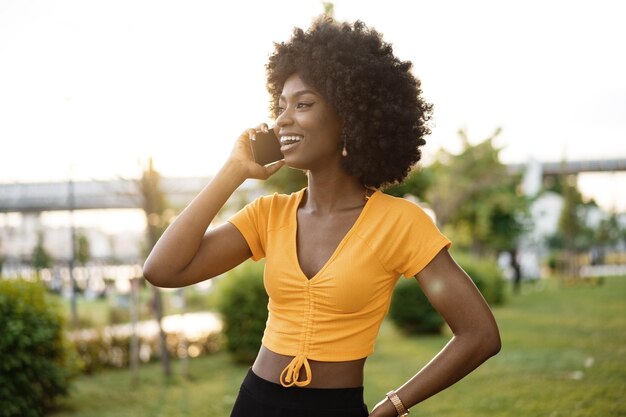 Gelukkig jonge Afro-Amerikaanse jonge vrouw praten met mobiele telefoon in de stad