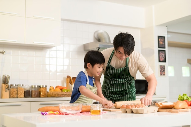 Gelukkig jonge Aziatische vader en zoon koken in de keuken thuis