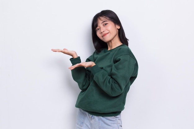 Gelukkig jonge Aziatische vrouw wijzend met de vingers naar verschillende richtingen geïsoleerd op een witte achtergrond