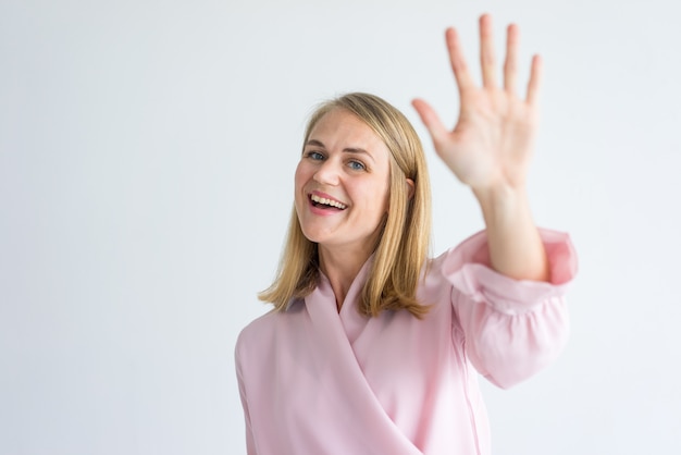 gelukkig jonge blanke zakenvrouw draagt ​​roze blouse zwaaien hand in groet