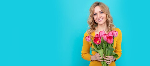 Gelukkig jonge blonde vrouw met lente tulp bloemen op blauwe achtergrond Vrouw geïsoleerd gezicht portret banner met mock up kopie ruimte