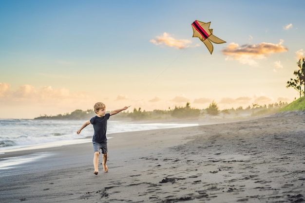 Gelukkig jonge jongen vliegeren op het strand bij zonsondergang