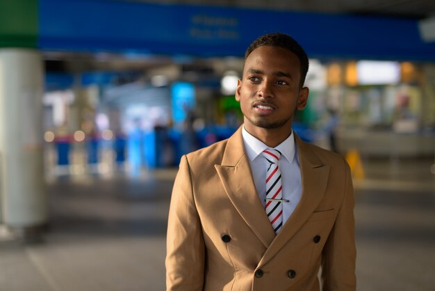 Gelukkig jonge knappe Afrikaanse zakenman weglopen vanaf het treinstation