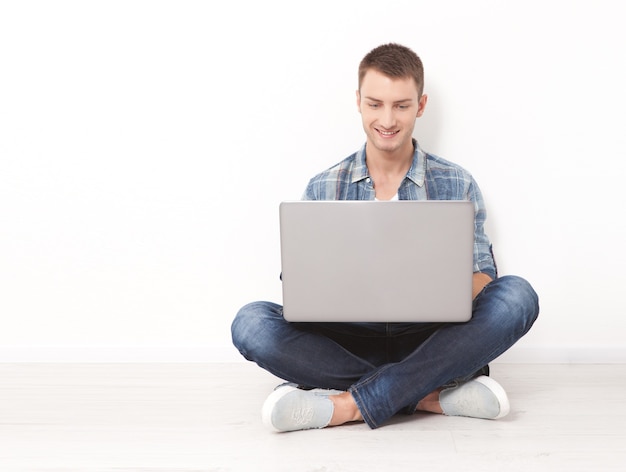 Gelukkig jonge man aan het werk op laptop geïsoleerd