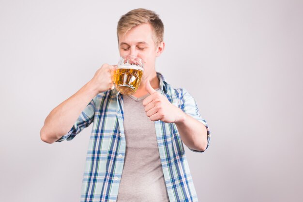 Gelukkig jonge man bierpul drinken en duimen opdagen