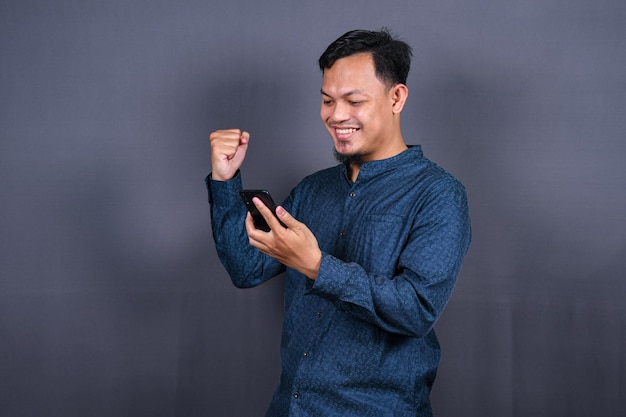 Gelukkig jonge man in blauw shirt poseren geïsoleerd op grijze achtergrond studio portret. levensstijl concept