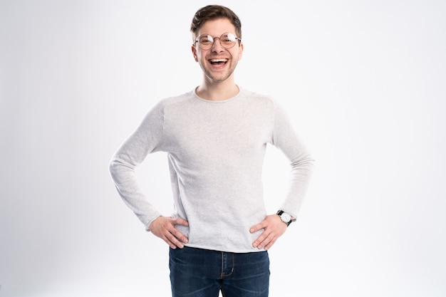 Gelukkig jonge man in casual shirt glimlachen terwijl staande tegen een witte achtergrond