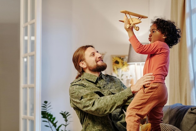 Gelukkig jonge man in militair uniform plezier met zijn schattige zoontje