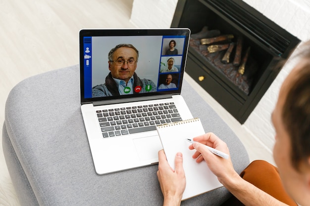 Gelukkig jonge man in t-shirt om thuis te zitten, werken op laptopcomputer, glimlachend.