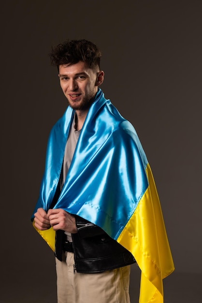 Gelukkig jonge man met Oekraïense vlag op zwarte achtergrond