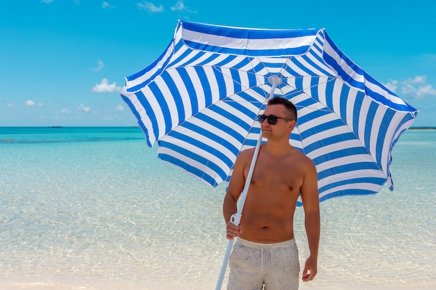 Gelukkig jonge man met parasol op het strand