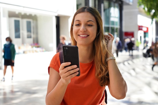 Gelukkig jonge mode vrouw kijken op mobiele telefoon in de stad