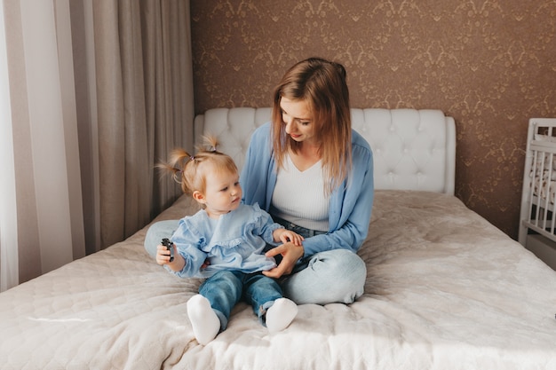 Gelukkig jonge moeder speelt met haar dochter op het bed thuis. Moederdag.