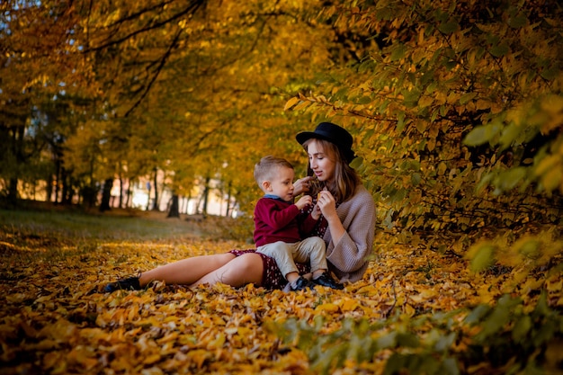 Gelukkig jonge moeder spelen met baby in herfst park met gele esdoorn bladeren. Familie buiten wandelen in de herfst