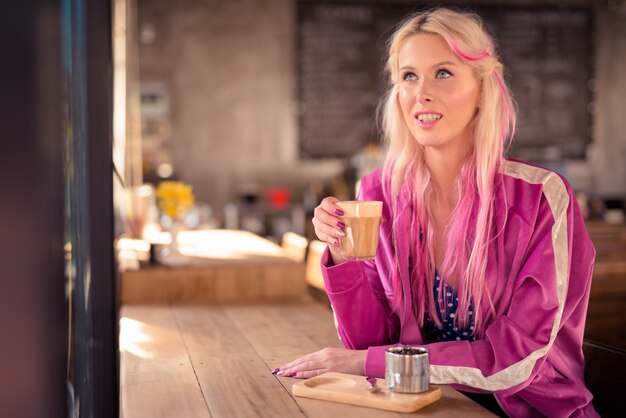 Gelukkig jonge mooie blonde vrouw denken en ontspannen in de koffieshop