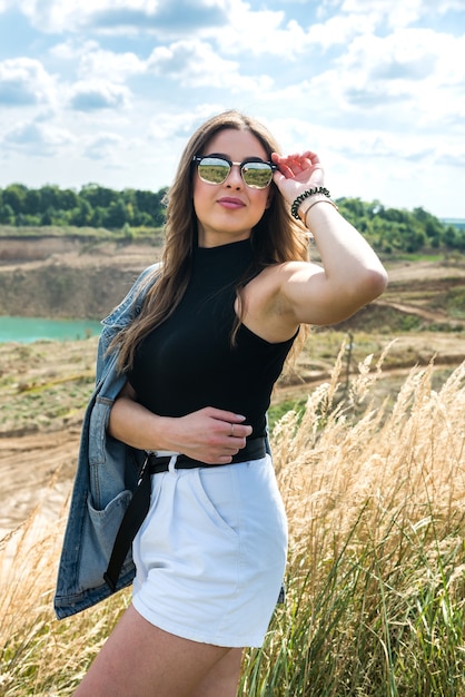 Gelukkig jonge mooie vrouw genieten van het landschap in de buurt van groene veld in de zomer