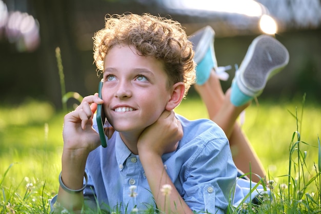 Gelukkig jonge tiener praten op mobiele telefoon buiten in zomer park. Online vriendschapsconcept.