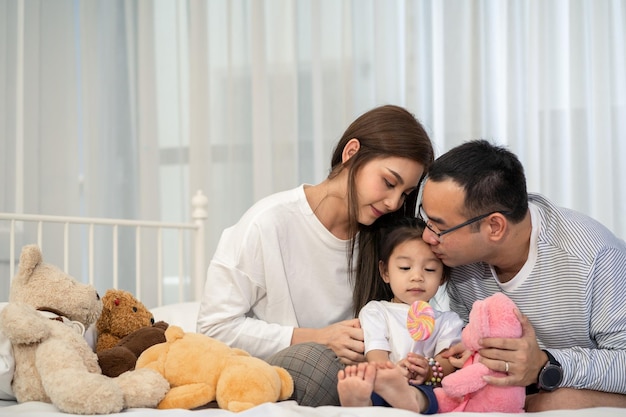 Foto gelukkig jonge vader en moeder en een dochtertje spelen met speelgoed zittend op de vloer in de woonkamer familie ouderschap en mensen concept