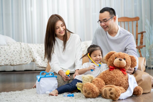 Gelukkig jonge vader en moeder en een dochtertje spelen met speelgoed, zittend op de vloer in de woonkamer, familie, ouderschap en mensen concept