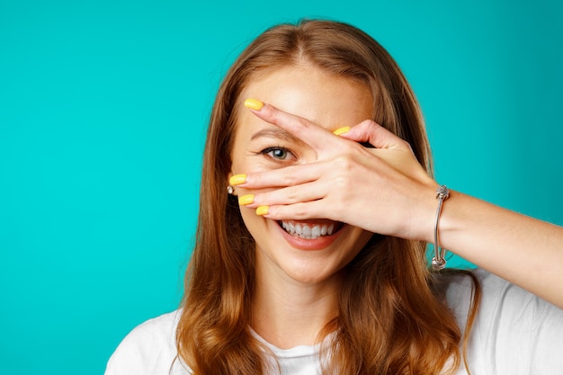 Gelukkig jonge vrouw gluren door haar vingers en glimlachen