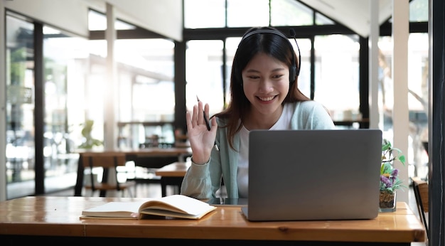 Gelukkig jonge vrouw in koptelefoon spreken kijken naar laptop maken van aantekeningen studente praten door video conference call vrouwelijke leraar trainer begeleiding door webcam online opleiding ecoaching conceptxA