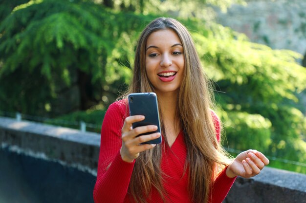 Gelukkig jonge vrouw met behulp van slimme telefoon-app buiten