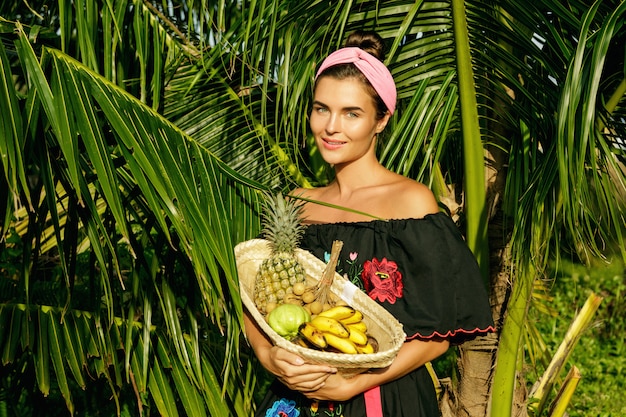 Gelukkig jonge vrouw met een mand vol exotische vruchten