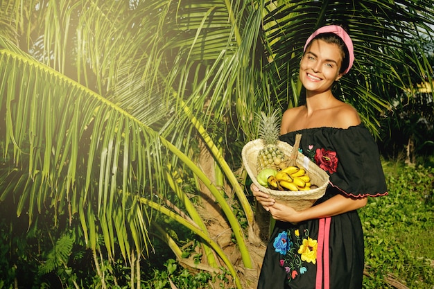 Gelukkig jonge vrouw met een mand vol exotische vruchten