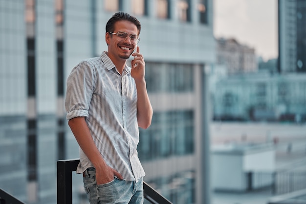 Gelukkig jonge zakenman praten op mobiele telefoon in de buurt van business center.