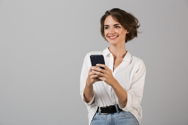 Gelukkig jonge zakenvrouw poseren met behulp van mobiele telefoon en chatten