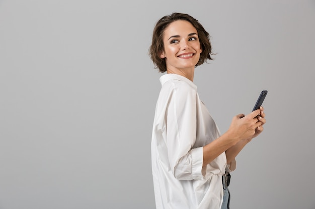 Gelukkig jonge zakenvrouw poseren met behulp van mobiele telefoon en chatten