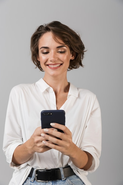Gelukkig jonge zakenvrouw poseren met behulp van mobiele telefoon en chatten