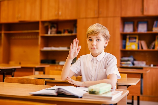 Gelukkig jongetje heeft idee. Schooltaak doen met veel boeken.